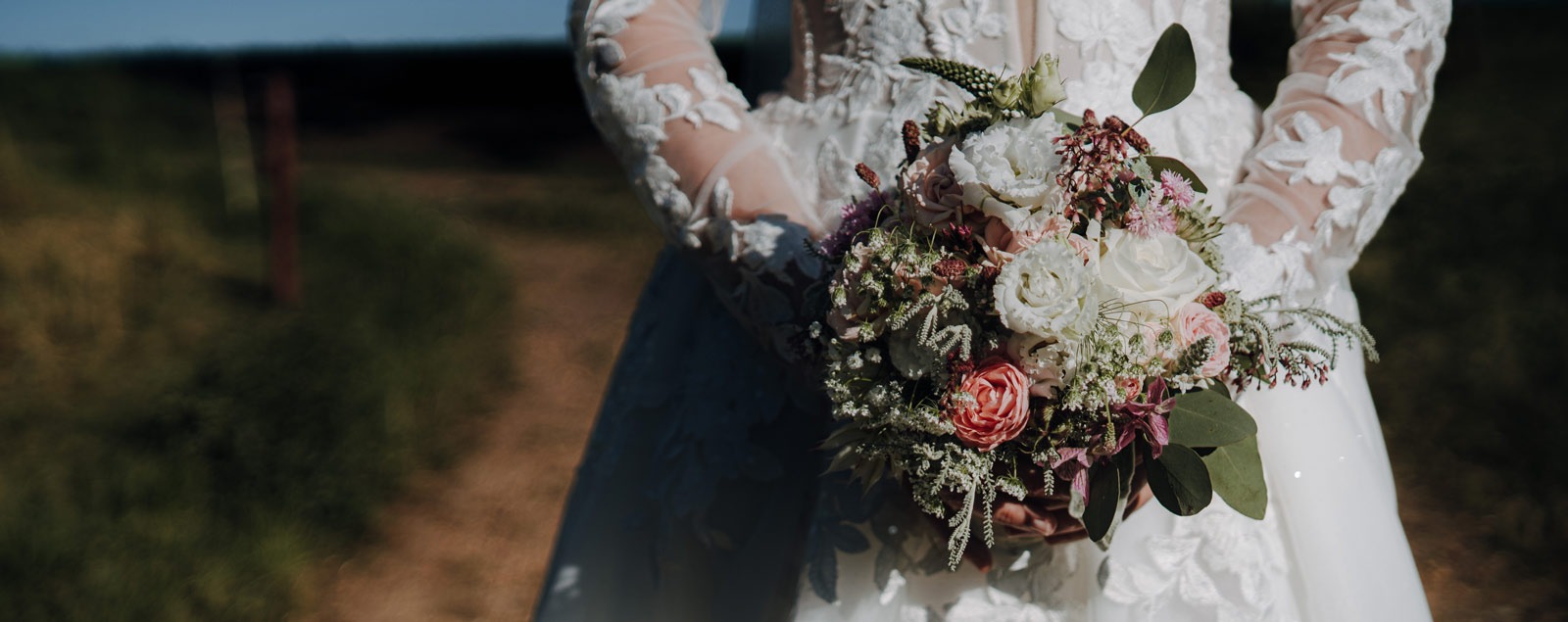 Hochzeitsfotografie Brautstrauß vor Brautkleid im Sonnenuntergang